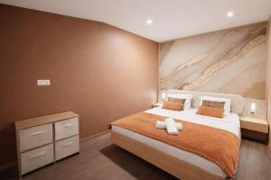 a bedroom with a large bed with an orange blanket at Le Saphir avec Parking gratuit in Montigny-le-Bretonneux