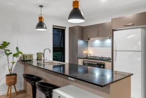 a kitchen with a black counter top and a refrigerator at JOT Luxe Haven in Narangba