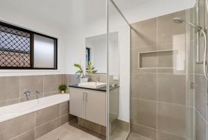 a bathroom with a tub and a sink and a shower at JOT Luxe Haven in Narangba +10 photos