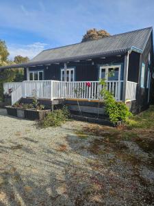 a black house with a porch and a white fence at The Blackhouse Cottage in Hokitika