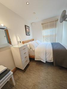 a bedroom with a bed and a dresser and a window at Cambridge city centre immaculate 2 bed apartment in Cambridge