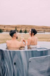 a man and a woman sitting in a hot tub at Nest Retreat Iceland - Mirror Houses by the Rangá river in Hella