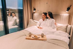 a man and a woman sitting on a bed at Nest Retreat Iceland - Mirror Houses by the Rangá river in Hella