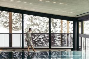 a woman walking in front of a large window at Hotel Kirchenwirt in Kaunertal