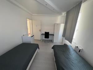 a small room with two beds and a desk at HostelCetin in Göppingen +8 photos
