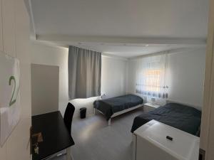a bedroom with two beds and a desk in it at HostelCetin in Göppingen