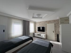 a bedroom with two beds and a flat screen tv at HostelCetin in Göppingen