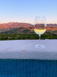 a glass of wine sitting next to a swimming pool at Casa Romeriko piscina privada vistas espectaculares Valle de Ricote Murcia in Ricote