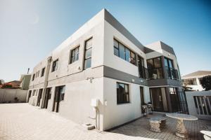 a white building with a table in front of it at Wave Inn Guesthouse in Valsbaai