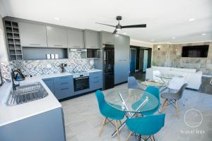 a kitchen with blue and white cabinets and chairs at Wave Inn Guesthouse in Valsbaai