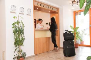 a woman standing at a reception desk with her luggage at Plus Hotel in Craiova