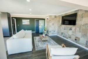 a living room with a white couch and a tv at Wave Inn Guesthouse in Valsbaai