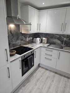 a kitchen with white cabinets and a stove top oven at Flat 8 in Plymouth