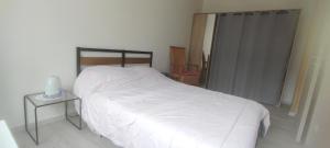 a bedroom with a white bed and a side table at Chambres Strasbourg in Strasbourg
