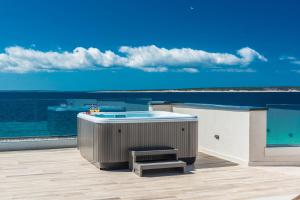 a deck with a tub and a bench and the ocean at Luxury Mandre Penthouse in Mandre