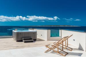 a deck with a hot tub and a bench and the ocean at Luxury Mandre Penthouse in Mandre