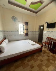 a bedroom with a bed and a chair and a television at Nhà nghỉ Phú Mỹ in Ấp An Mỹ