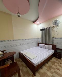 a bedroom with a bed and a table and a ceiling at Nhà nghỉ Phú Mỹ in Ấp An Mỹ