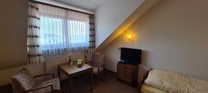 a small room with a bed and a tv and a table at Pension Hauber - Hotzenwaldblick in Herrischried