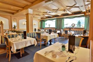 un comedor con mesas y sillas blancas en Berghotel Tyrol, en Senales