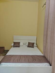 a bed in a room with two pillows on it at Tataicha Appart 3 in NʼDjamena