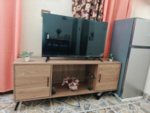 a flat screen tv on a wooden entertainment center at Tataicha Appart 3 in NʼDjamena