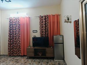a room with red curtains and a tv and a televisionictericter at Tataicha Appart 3 in NʼDjamena