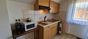 a small kitchen with a microwave and a sink at Pension Hauber - Kirchturmblick in Herrischried +8 photos