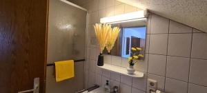 a bathroom with a mirror and a vase with yellow flowers at Pension Hauber - Kirchturmblick in Herrischried