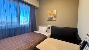 a small room with two beds and a window at Hotel Route-Inn Natori Iwanuma Inter -Sendai Kuko- in Natori