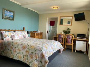 a bedroom with a bed and a desk with a microwave at Citrus Grove in Nelson
