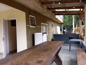 a large wooden table in a patio with a refrigerator at Casa da Colina Curitiba com piscina in Curitiba