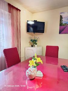 a dining room table with red chairs and a vase with flowers at Rural accommodation Vidovic in Ugarci