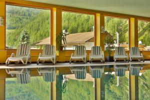 a row of chairs sitting next to a swimming pool at Berghotel Tyrol in Senales