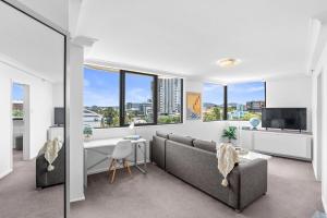 a living room with a couch and a desk and windows at Riverview Sanctuary - Walk to CBD & South Bank in Brisbane