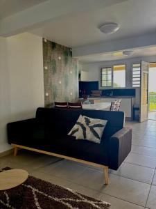 a living room with a blue couch and a kitchen at Residence la Floride in Gros-Morne