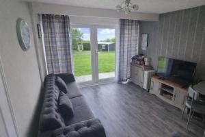 a living room with a couch and a television at Watkin - Snowdon Cabins - cozy chalet - Glan Gwna, Caernarfon in Caeathro