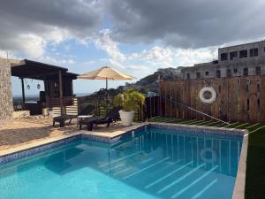 a swimming pool with a table and an umbrella at 360 RokView Suites 3BR Spacious in Kingston