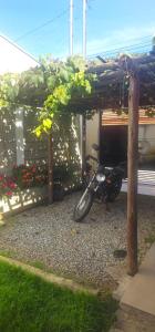 a motorcycle is parked under a wooden pergola at Quarto Aconchegante com Wi-Fi self check-in e garagem in Pouso Alegre