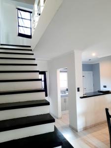 a staircase in a home with white walls and black floors at Duplex familiar zona macrocentro in Resistencia