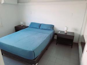 a bedroom with a bed with blue sheets and two tables at Duplex familiar zona macrocentro in Resistencia