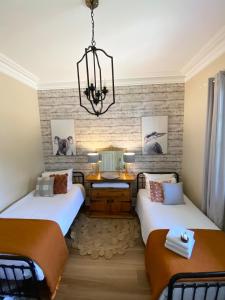 a bedroom with two beds and a chandelier at Korumburra Farmhouse in Korumburra