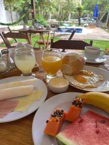 a wooden table with plates of breakfast foods and drinks at Pousada ViniCarmel Arraial D'ajuda in Arraial d'Ajuda