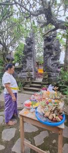 a woman standing next to a table with food on it at Serongga guest house in Lebih