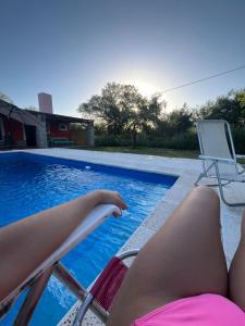 a woman laying on a chair next to a swimming pool at Los dos Algarrobos in Villa Dolores