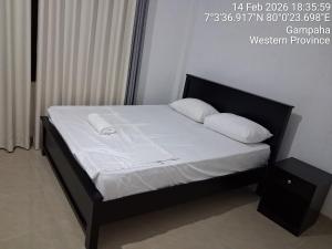 a bed with a black frame and white sheets and pillows at Layans Properties in Gampaha +7 photos