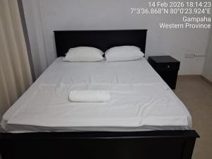 a bed with white sheets and pillows on it at Layans Properties in Gampaha