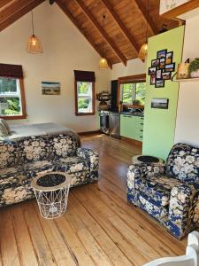 a living room with two couches and a kitchen at The Blackhouse Cottage in Hokitika