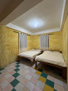 two beds in a room with a tiled floor at Mama Lourdes Homestay in Sagada