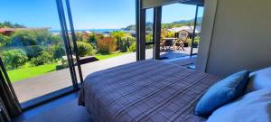 a bedroom with a bed and a view of a deck at Cedar Cottage in Takaka
